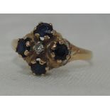 A lady's dress ring having a four stone sapphire open cluster with central diamond chip and