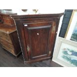 An early 19th century oak corner wall cupboard having panel door