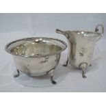 A silver sugar bowl and cream jug of plain form having decorative rims and paw feet, Birmingham