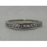 A lady's half eternity ring having 13 channel set diamond chips on a white metal loop stamped 750,