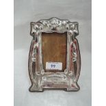 An Arts and Crafts style white metal photograph frame having moulded seed pod decoration and