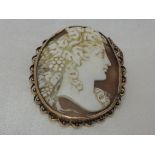 A conche shell cameo brooch depicting a bacchanalian maiden in profile in a decorative yellow