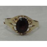 A gents 9ct gold signet ring having a garnet in an open setting, size U