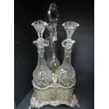 An Edwardian silver plated three bottle decanter holder containing three tall cut glass bottles (