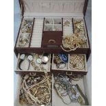 A tan leather effect jewellery box containing a selection of costume jewellery including clip