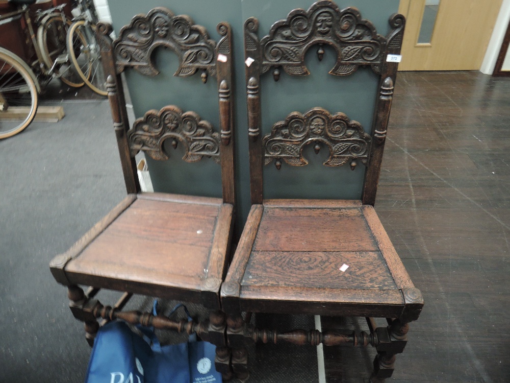 A pair of late Victorian oak carolean style hall chairs having carved moon face and cloud rail