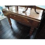 A late 19th/early 20th century stained pine kitchen table having drop leaf top on turned legs