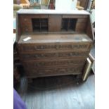 A 19th century oak bureau having later extensive carved scroll and roundel decoration, with fitted
