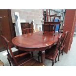 An Oriental hardwood extending dining table and chairs