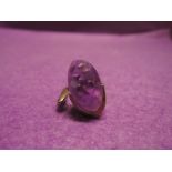 A lady's dress ring of stylised form having an oval purple stone on an open white metal loop stamped