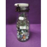 A glass jar containing various design marbles