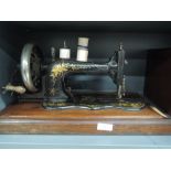 An antique Frister and Rossmann hand cranked sewing machine with wooden case