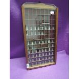 A wooden wall hanging thimble case containing a selection of thimbles including HM