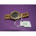 A gents gold plated fashion watch bearing name Rolex having a black face and diamante besel on