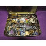 A vintage tobacco tin containing a selection of religious medallions, souvenir brooches etc