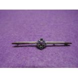 A yellow metal bar brooch stamped 9ct having a powder blue sapphire open square cluster
