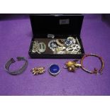 A small case containing a selection of costume jewellery including brooches and bracelets