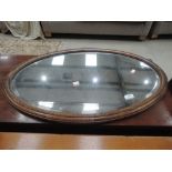 An early 20th Century oak oval wall mirror