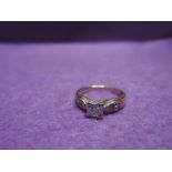 A lady's dress ring hsving a diamond solitaire, approx 0.128ct in a square mount to diamond set