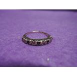A half eternity ring having five sapphires interspersed by diamond chips in an illusionary mount