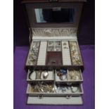 A tan leather effect jewellery box containing a selection of costume jewellery including clip