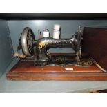 An antique Frister and Rossmann hand cranked sewing machine with wooden case