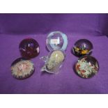 A selection of colour glass paper weights including named brands