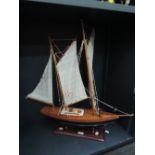 A modern wooden model sail boat on display plinth