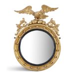 A CARVED GILTWOOD CONVEX MIRROR, 19th century, of circular form surmounted by an eagle, perched on