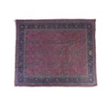 A PERSIAN RED GROUND WOOL CARPET, woven with scattered floral motifs, within multiple guard