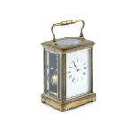 AN EDWARDIAN BRASS CASED CARRIAGE CLOCK, the bevelled glass panels enclosing a white enamel dial and