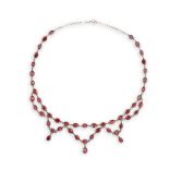 A SILVER AND GARNET NECKLACE, composed of oval-shaped garnets within collet and millegrain