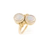 AN OPAL AND DIAMOND CROSS OVER RING, of classical design set with two round opals each encircled