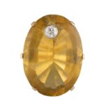 A LARGE CITRINE AND DIAMOND STUDDED COCKTAIL RING, of oval shape, with single collet-set round