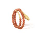 A CORAL, EMERALD AND GOLD SERPENT BRACELETDesigned as a scrolling serpent, the body decorated with