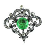Broche S. XIX con esmeralda central de talla redonda, rodeada por marco de de diamantes y brillantes