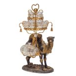 Licorera de bronce patinado con forma de camello y vasos transparentes pintados. Quizás trabajo