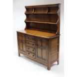 An Ercol elm dresser, fitted two open shelves to the panelled back, the base fitted four long