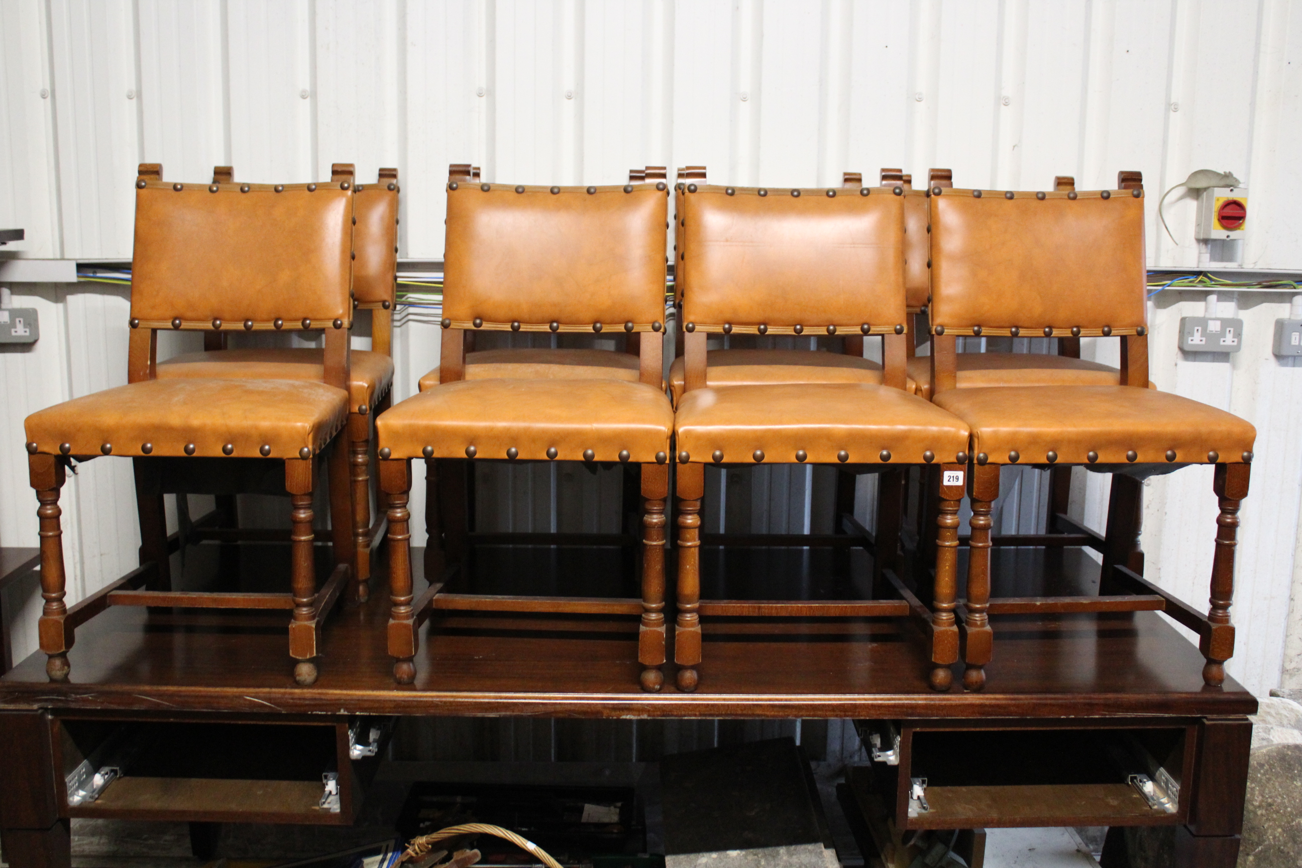 A set of eight oak dining chairs with padded seats & backs upholstered brown leatherette, & on