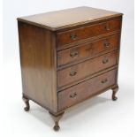 A reproduction walnut small chest, fitted four long graduated drawers with brass swing handles, & on