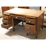 An oak kneehole office desk, fitted with an arrangement of two brushing slides & six drawers, & on