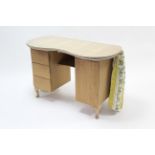 A kidney-shaped dressing table fitted three long drawers to the left-hand pedestal & with cupboard