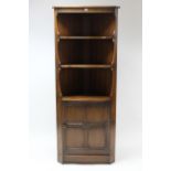 An Ercol elm tall standing corner unit fitted two shaped open shelves above cupboard enclosed by