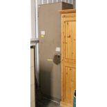 A pale brown art-metal tall locker, enclosed by door, with key, 24” wide x 84” high.