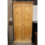 A pine wardrobe, enclosed by pair of panel doors, & on plinth base, 37” wide x 76” high.