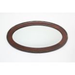 An Edwardian mahogany frame oval wall mirror inset bevelled place, & with beaded edge (slight