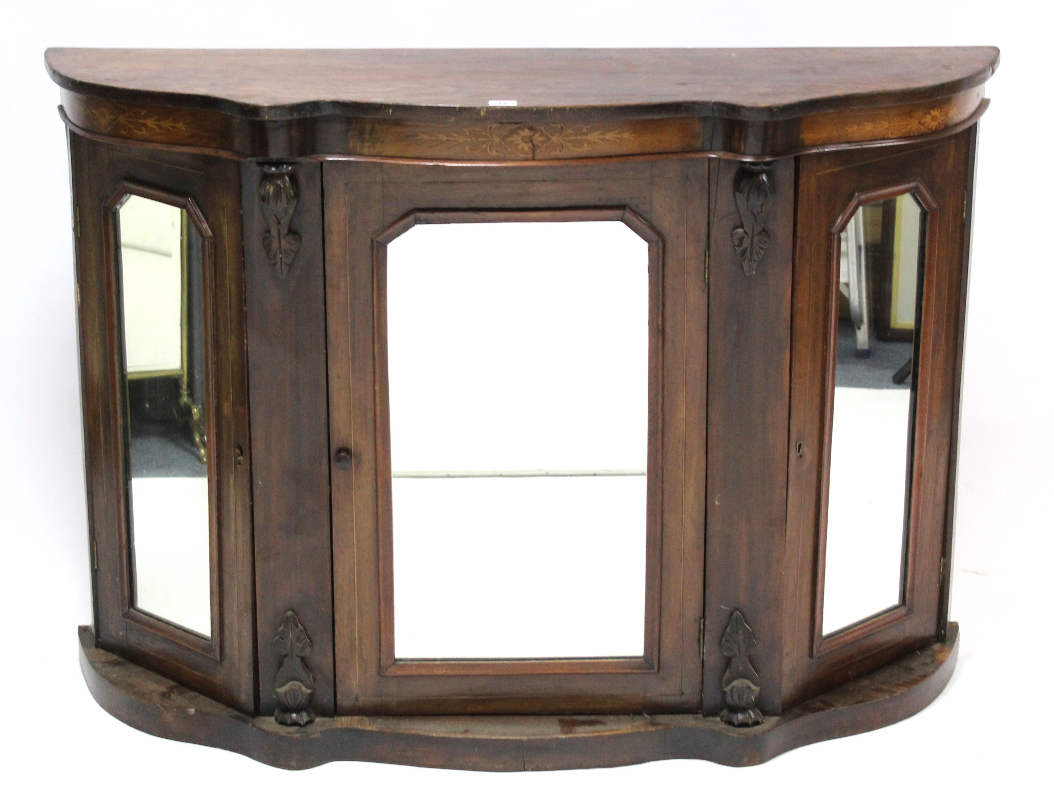 A 19th century marquetry-inlaid serpentine-front cabinet enclosed by three mirror doors, & on shaped