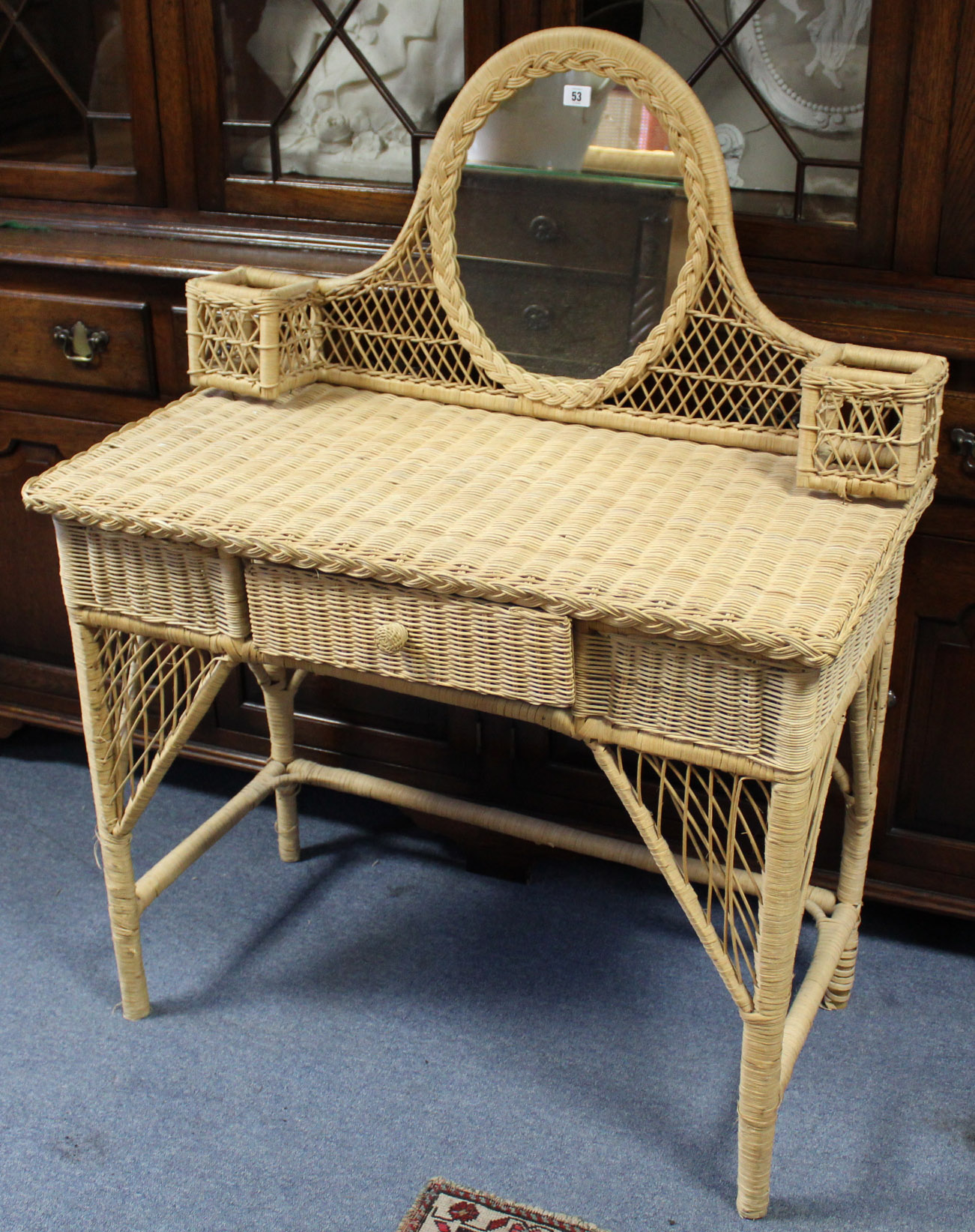 A wicker dressing table, inset oval mirror to the stage back, & fitted centre frieze drawer, 36¼”