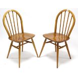 A pair of Ercol light elm spindle-back dining chairs, with hard seats & on round tapered legs with