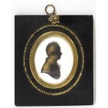 An early 19th century silhouette profile portrait of a young gentleman, on plaster & heightened in